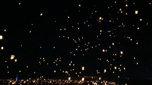 4K video of floating sky lanterns at night in the desert.