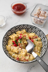 Bowl of tasty chicken curry on light background