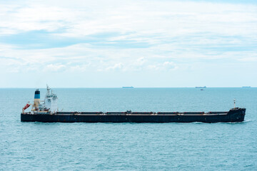 Bulk carrier ship, sailing through calm, blue sea.
