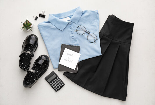 Stylish school uniform, stationery, eyeglasses and paper sheet with text BACK TO SCHOOL on light background