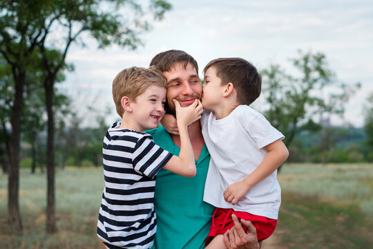 Caring father with two little sons on countryside background. Authentic family portrait of dad and children outdoors