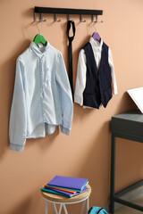 School uniform hanging on color wall