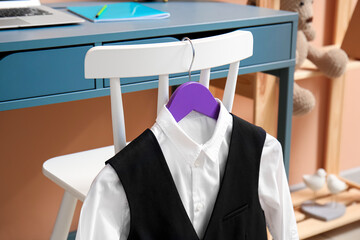 Stylish school uniform hanging on chair in room