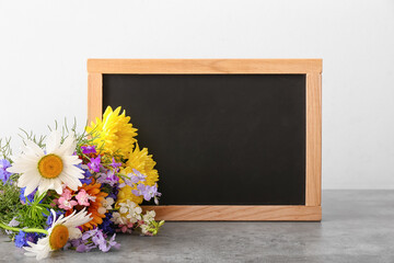 Blank chalkboard and bouquet of beautiful flowers on table