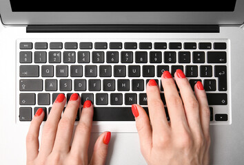 Woman with beautiful manicure working with laptop, closeup