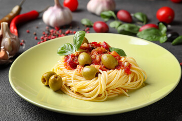 Plate with tasty Pasta Puttanesca on dark background
