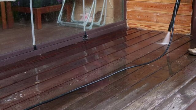 Man cleaning walls and floor with high pressure power washer. Washing terrace wood planks and cladding walls. High quality 4k footage