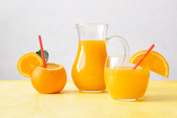 Jug and glass of tasty orange juice on table