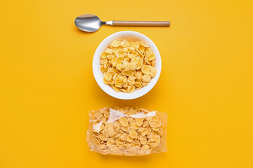 Bowl and bag with tasty cornflakes on color background
