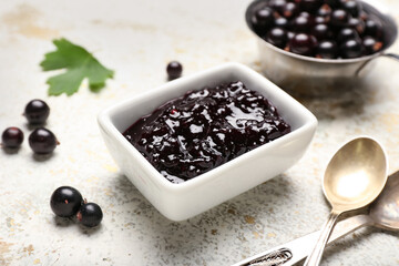 Bowl with delicious black currant jam on light table