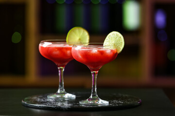 Glasses of tasty strawberry margarita on table in bar