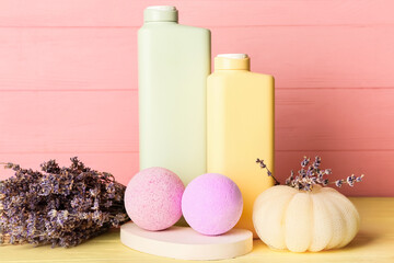 Bath bombs and bottles of cosmetic products on color wooden background