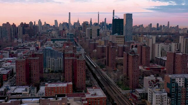 Epic aerial stationary shot of commuter train heading through a housing project in Harlem New York City down into Midtown Manhattan