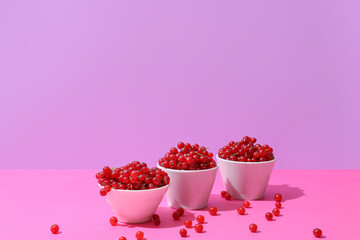 Bowls with fresh red currants on color background