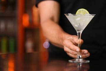 Male bartender with glass of tasty margarita cocktail in bar