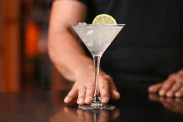 Male bartender with glass of tasty margarita cocktail in bar