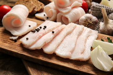 Board with slices of salted lard on wooden background