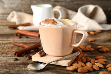Cup of tasty almond latte with cinnamon on wooden background