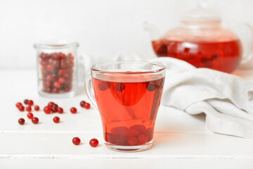 Cup of tasty tea with cranberry on light wooden background
