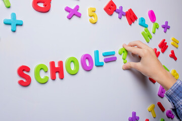 smart schoolchild standing at blackboard and holding colorful letters