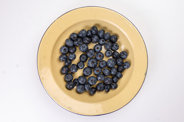 Fresh ripe deep purple Blueberry on old style metal enamel tin plate macro closeup top view