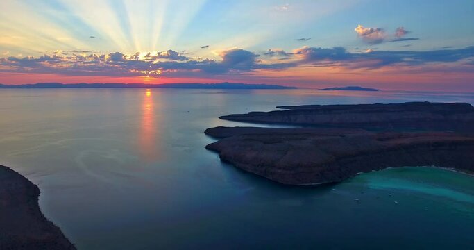 Hover View of Sunset with Light Rays through Clouds and Boats in the Background