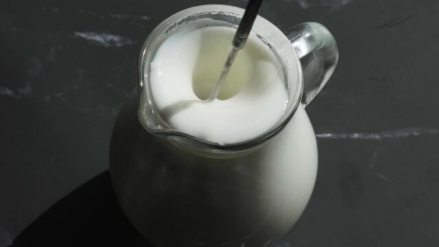 Beat the milk in a mug using a frother. Hand mixer for milk. Making foamy with frother. Preparing milk for coffee. Step by step. Jug appliance starting up and turning around to froth white causing bub