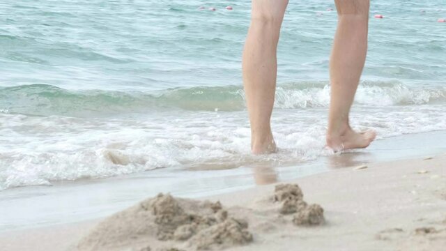 Barefoot man legs feet walking on beach ocean water. Summer vacation, holiday, family trip. Tourism to warm countries.