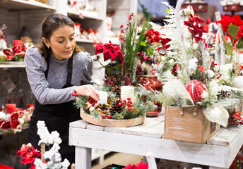 Smiling flower shop worker making christmas compositions