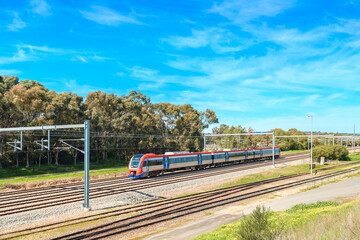 Electric passenger train departing from the Mile End Railway Station and heading to Adelaide city on a bright day