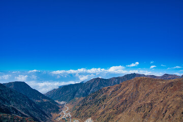 The natural scenery of the tawny mountains under the blue sky and white clouds. View of the mountains along the way. Travel to the Tsomgo Lake (Changu Lake), in the Indian state of Sikkim.