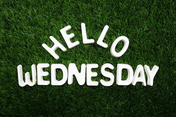 Hello Wednesday alphabet letter on green grass background