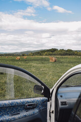 view of the autumn field with haystacks from behind the car door. the atmosphere of car trips. content of vertical travel, selective focus