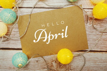 Hello April typography text with LED cotton ball on wooden background