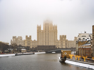 Obraz na płótnie Canvas View to Kotelnicheskaya Embankment Building in the morning fog in winter. The spire hiding in the fog. Stalinist skyscraper on Kotelnicheskaya embankment in Moscow, Russia