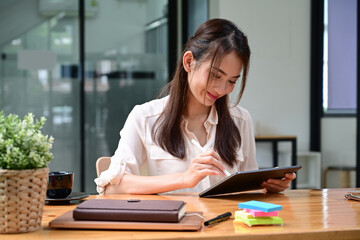 Smiling businesswoman using digital tablet at office.