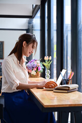 Female freelancer sitting in coffee shop and working with computer laptop.