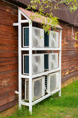 A rack with a group of air conditioners on the facade of a wooden house made of timber
