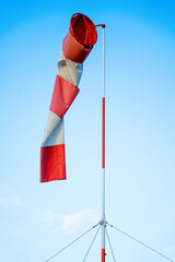 A red and white cone for measuring the strength and direction of the wind hangs motionless, calm