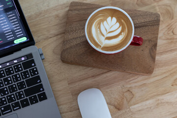Top view red cup of coffee latte and laptop on wooden table.
