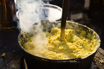 cauldron with polenta while cooking with wooden ladle