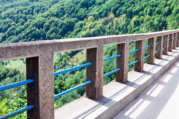 Fototapeta premium Balustrade of The Durdevica Tara Bridge in Montenegro . Green forest treetops view from the bridge 