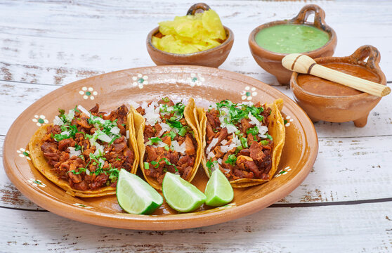 Tacos al pastor, tradicional comida mexicana, con cebolla, cilantro, pi&ntilde;a, salsa roja o guacamole.