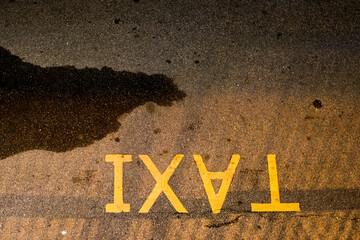 The shape of the inverted yellow English letters written on the road reads TAXI.