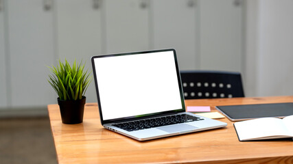 Laptop blank white screen with documents placed on wooden office desk.