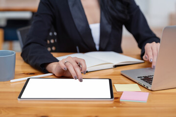 Close-up of businesswoman holding pen working using tablet  blank white screen and keyboard laptop at office.
