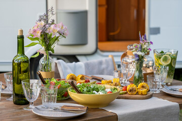 Homemade vegetarian food on wooden table served for dinner against house on wheels