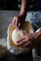 Woman baker forms bread and puts in a basket