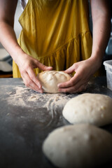 Fototapeta premium Woman baker forms bread on a steel table in a bakery