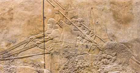 Assyrian wall relief of lion hunt, king Ashurbanipal with warriors on carving from Middle East and Mesopotamia. History of past civilization of Iran and Iraq. Monument of Assyria and Babylon culture.